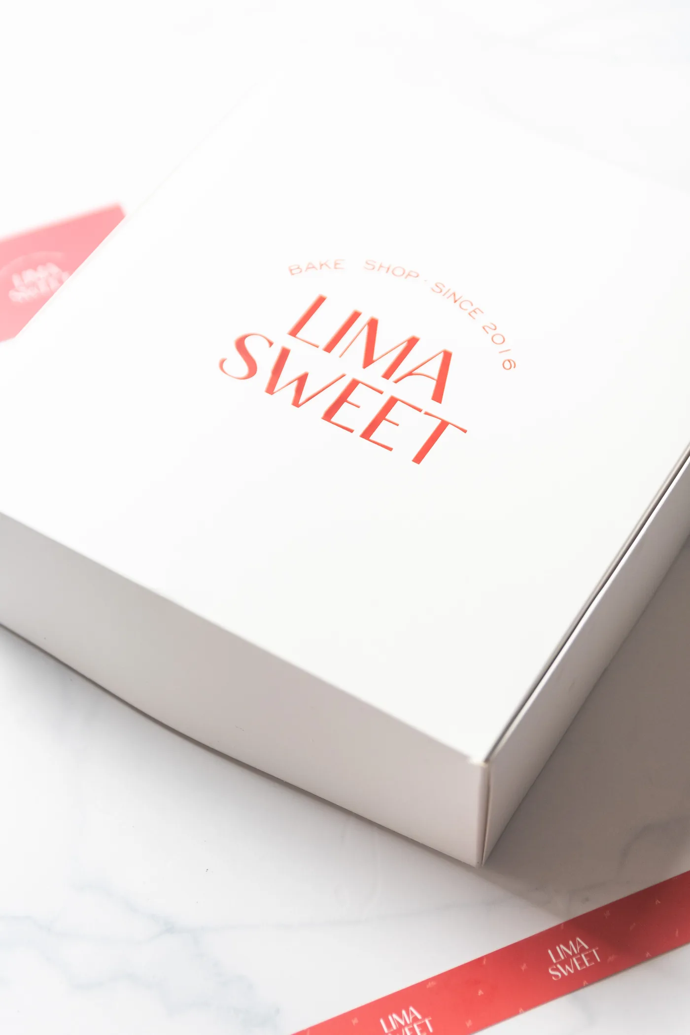 Caja de repostería Lima Sweet con cinta y sticker de la marca