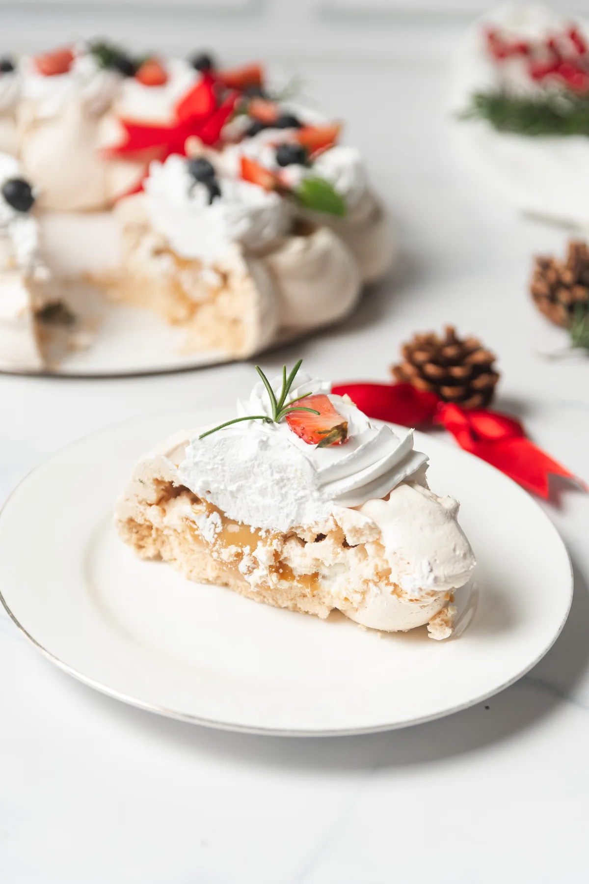 Porción de pavlova con caramelo, romero y fresa, en su ambientación navideña